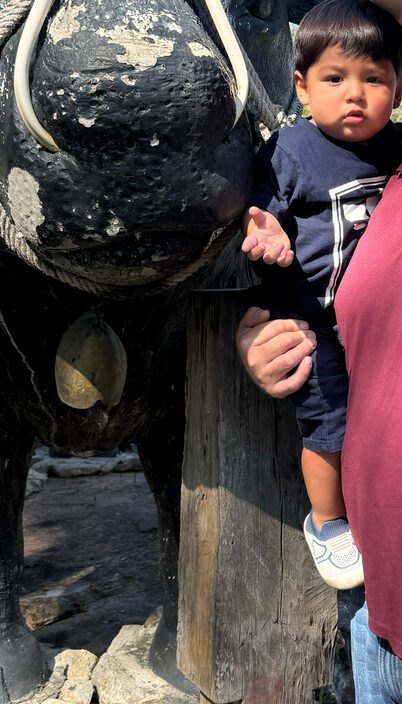 One of the Cunningham boys beside a bull statue in Texas