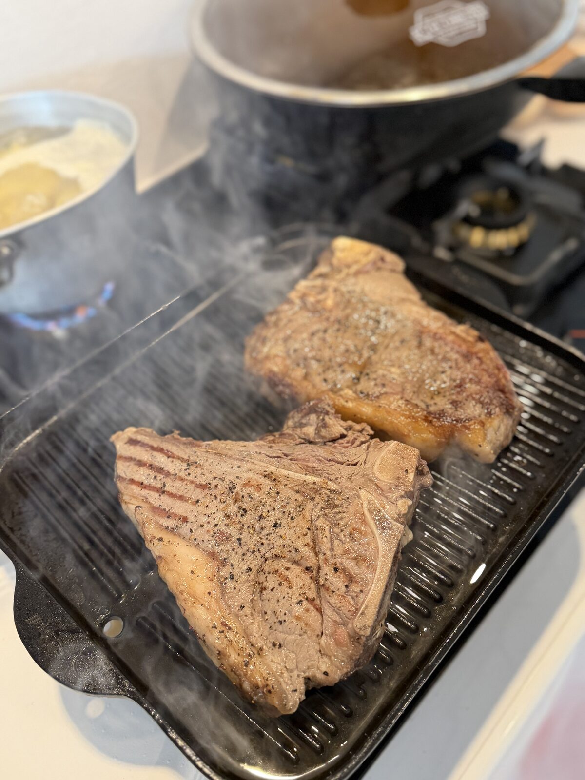 Two porterhouse steaks searing on Ben's cast iron grill